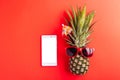 Celebrate Summer Pineapple Day Concept, Top view of funny pineapple wear red sunglasses and smartphone blank screen, isolated