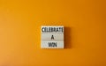 Celebrate a win symbol. Concept words Celebrate a win on wooden blocks. Beautiful orange background. Business and Celebrate a win