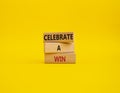 Celebrate a win symbol. Concept words Celebrate a win on wooden blocks. Beautiful yellow background. Business and Celebrate a win Royalty Free Stock Photo