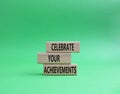 Celebrate your achievements symbol. Concept words Celebrate your achievements on wooden blocks. Beautiful green background.