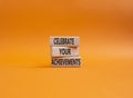 Celebrate your achievements symbol. Concept words Celebrate your achievements on wooden blocks. Beautiful orange background.