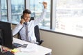 Celebrating Businessman Making Phone Call At Desk In Office Royalty Free Stock Photo