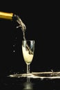 Golden champagne poured from a bottle into a glass, visible drops, bubbles and a splash