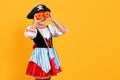 Celebrating Halloween. Cheerful girl in a carnival costume of a pirate in the studio on a yellow background. Royalty Free Stock Photo