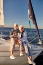 Celebrating love. Full length of cheerful senior family couple drinking wchampagne while sitting on a sailboat floating Royalty Free Stock Photo