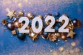 Celebrating the new year 2022. Date numbers 2022 on a background of Christmas toys, balls, streamer, sparkles.