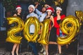 Celebrating New Year party. Group of cheerful young girls in beautiful wearing carrying gold colored numbers 2019 and Royalty Free Stock Photo