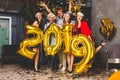 Celebrating New Year party. Group of cheerful young girls in beautiful wearing carrying gold colored numbers 2019 and Royalty Free Stock Photo