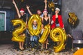 Celebrating New Year party. Group of cheerful young girls in beautiful wearing carrying gold colored numbers 2019 and Royalty Free Stock Photo