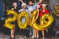 Celebrating New Year party. Group of cheerful young girls in beautiful wearing carrying gold colored numbers 2019 and Royalty Free Stock Photo