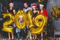 Celebrating New Year party. Group of cheerful young girls in beautiful wearing carrying gold colored numbers 2019 and Royalty Free Stock Photo
