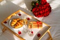 Celebrating Saint Valentine`s Day with bouquet of red roses, glass of champagne and croissants Royalty Free Stock Photo