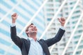 Celebrating success.Excited cheerful young businessman keeping arms raised and expressing positivity while standing outdoors with