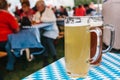 Two mugs with a light and dark beer stand on the table. In the background, blurred people. Celebrating the traditional Royalty Free Stock Photo