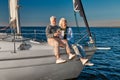 Celebrating wedding anniversary. Happy senior couple drinking wine or champagne and laughing while sitting on a sailboat Royalty Free Stock Photo