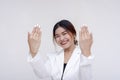 A celebrating young asian woman holding her hands up to show her engagement ring. Isolated on a white background