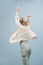 Celebrating young woman with stylish blond afro braids from behind over blue