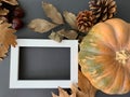 Celebration autumn Thanksgiving composition mock up with white photo frame, pumpkin, leaves and pine cones