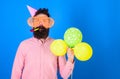 Celebration concept. Hipster in giant sunglasses celebrating birthday. Man with beard and mustache on calm face blows