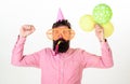 Celebration concept. Man with beard and mustache on busy face blows into party horn, white background. Guy in party hat