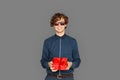 Celebration Concept. Teenager boy in sunglasses standing isolated on grey with present smiling cheerful Royalty Free Stock Photo