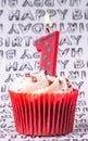Celebration cupcake with white icing and number candles showing 1 Royalty Free Stock Photo