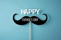 Celebration of Father's Day with playful mustache prop and bold lettering against blue background