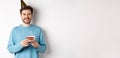 Celebration and holidays concept. Happy young man in party hat celebrating birthday, holding bday cake and smiling