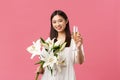 Celebration, party holidays and fun concept. Smiling pretty glamour asian woman in dress with white lilies bouquet
