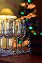 Celebration table with champagne glasses and stacked plates on christmas tree background