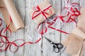 Celebratory concept - set with handmade present box in kraft paper, wrapping tools, packing paper on wooden background. Royalty Free Stock Photo