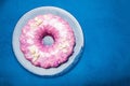 Celebratory round cake with pink icing on a blue background Royalty Free Stock Photo