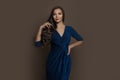 Celebrity brunette woman wearing blue evening gown standing on brown background Royalty Free Stock Photo