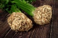 Celeriac / turnip-rooted celery roots with green leaves on dark wooden board, closeup detail
