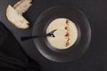 Celery cream soup in black plate over dark background from above