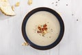 Celery cream soup in dark plate on white rustic background from above