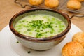 Celery cream soup with a green pea in a bowl garnished with chopped green onion and served with freshly baked cheese bread close- Royalty Free Stock Photo