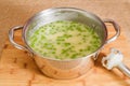 Celery cream soup with green pea close-up in a pan on the kitchen table Royalty Free Stock Photo