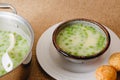 Celery cream soup with a green pea served with freshly baked cheese bread close-up on rustic background Royalty Free Stock Photo