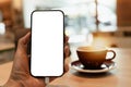 Cell Phone Blank White Screen Mockup.Woman Hand Holding Smart Mobile Phone,using social media with blurry coffee shop background, Royalty Free Stock Photo