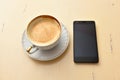 Cell phone and coffee cup on a vintage table Royalty Free Stock Photo