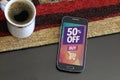 Cell phone with a 50% discount advertising on screen.