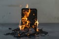 A cell phone engulfed in flames rests ominously on a table, emanating smoke and heat in a dramatic display of