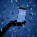 A cell phone is seen in a silhouetted hand in a shower of confetti