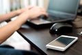 Cell phone (smartphone) on a table and woman working on the laptop computer