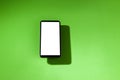 Cell phone with white screen on top of a green table. smartphone concept. Royalty Free Stock Photo