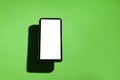Cell phone with white screen on top of a green table. smartphone concept. Royalty Free Stock Photo