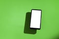 Cell phone with white screen on top of a green table. smartphone concept. Royalty Free Stock Photo