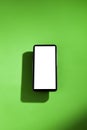 Cell phone with white screen on top of a green table. smartphone concept. Royalty Free Stock Photo