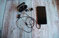 Cell phone with wired headset and bluetooth headset, on top of a wooden table. Royalty Free Stock Photo